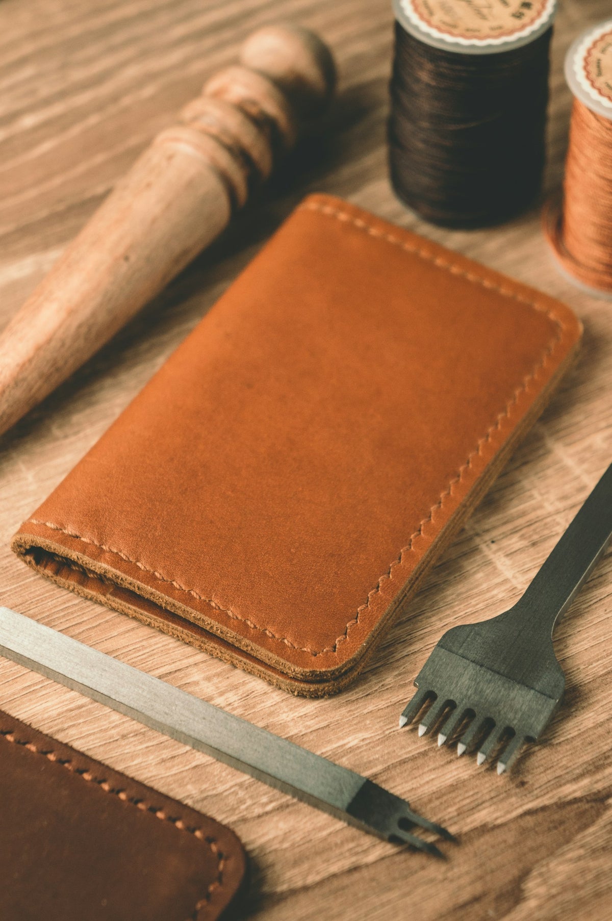Leather wallet with thread and scissors on a workbench